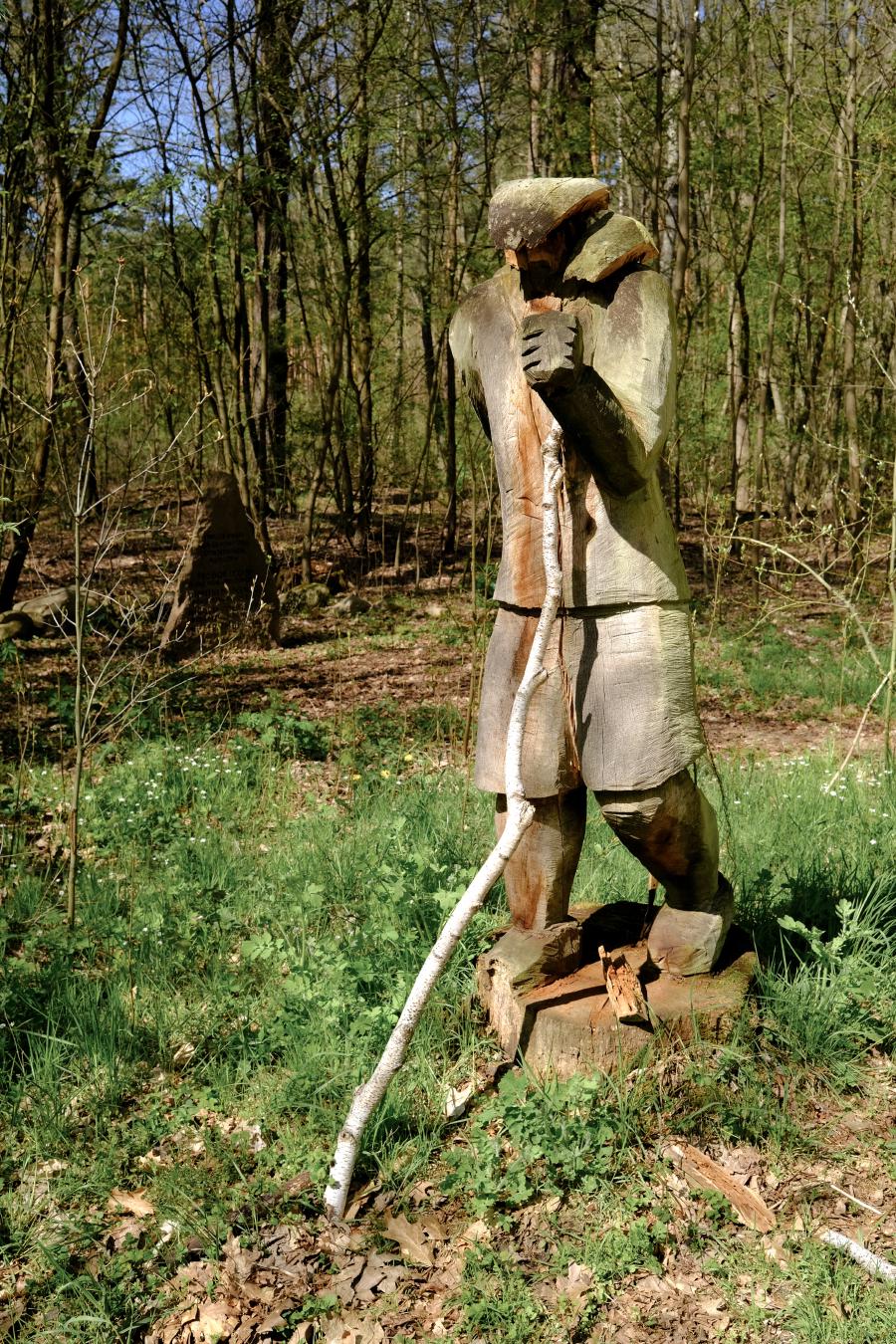 Kopfloser Wanderer aus Holz, im Hintergrund das Mahnmal für die gefallenen sowjetischen Soldaten